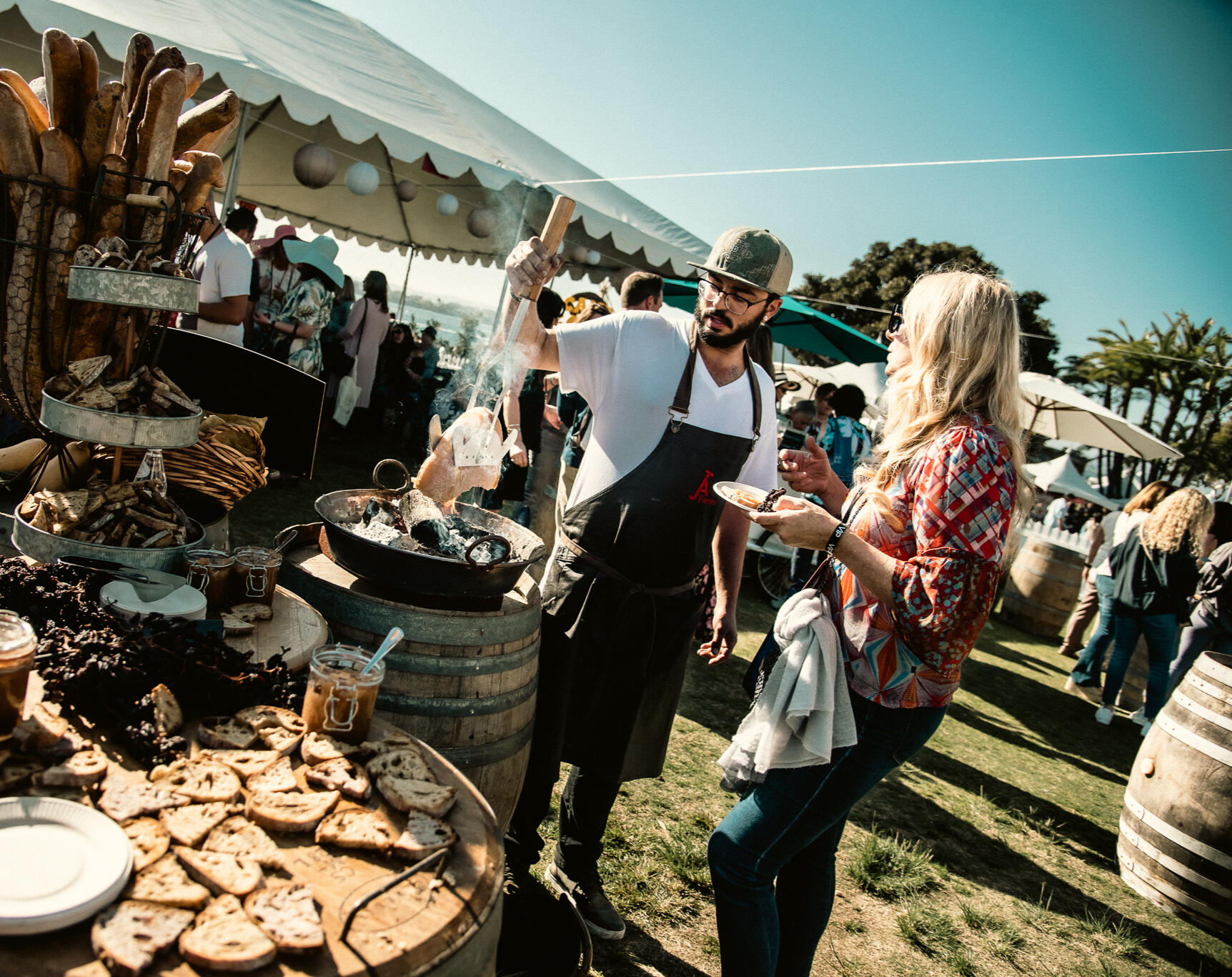 Chef serving food at upscale outdoor event, captured in candid documentary style with dynamic natural light and real expressions.