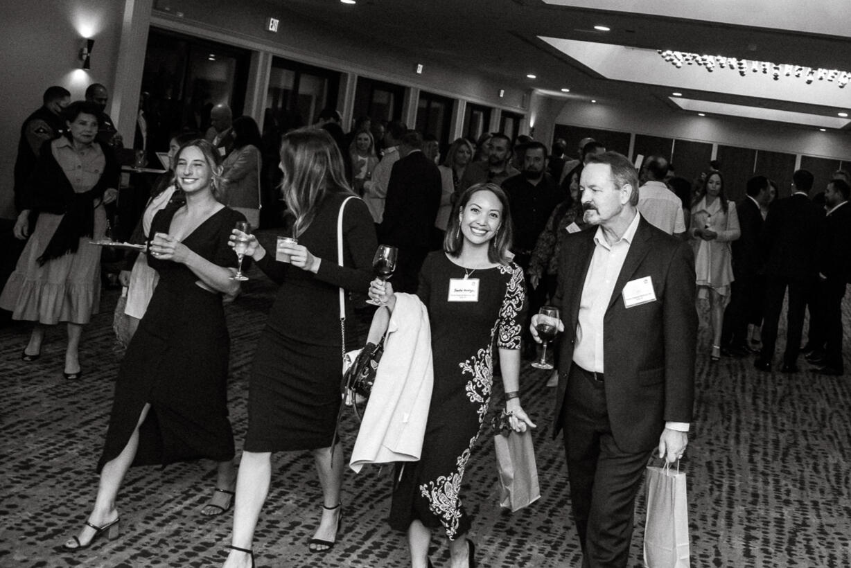 Group of professionals networking at a formal event, captured in high-contrast black-and-white documentary style.
